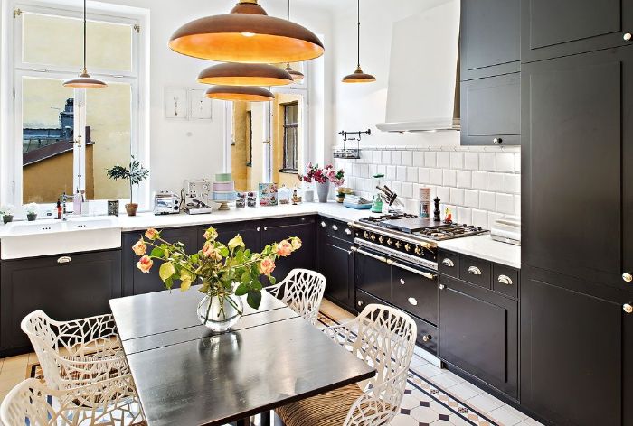 exemple pour aménager sa cuisine noire au carrelage blanc suspensions laiton table bois chaises metalliques blanches