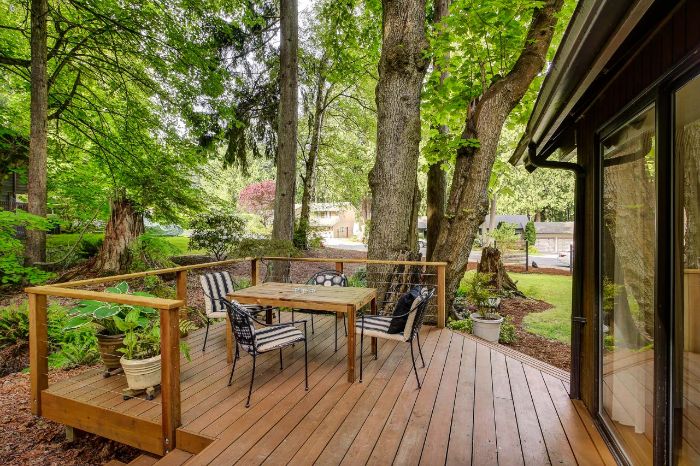 idee deco terrasse simple avec chaises en metal et table bois sur une terrasse de bois devant maison entourée de vegetation