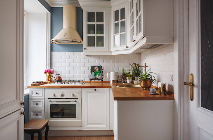 idée rangement petite cuisine d angle avec des comptoirs en bois et des meubles blanches un aspirateur beige au mur