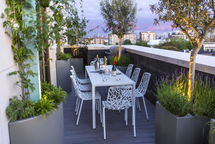 idée pour aménager sa terrasse plancher bois chaises et table blanche arbres en pot de terrasse