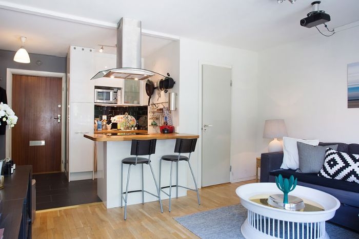 kitchenette pour studio 20 m2 avec carrelage noir meuble cuisine blanc ilot chaises noires ouverture sur salon gris et blanc