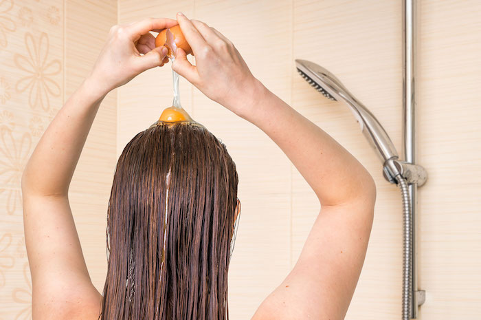 woman applying egg conditioner on her hair in bathroom