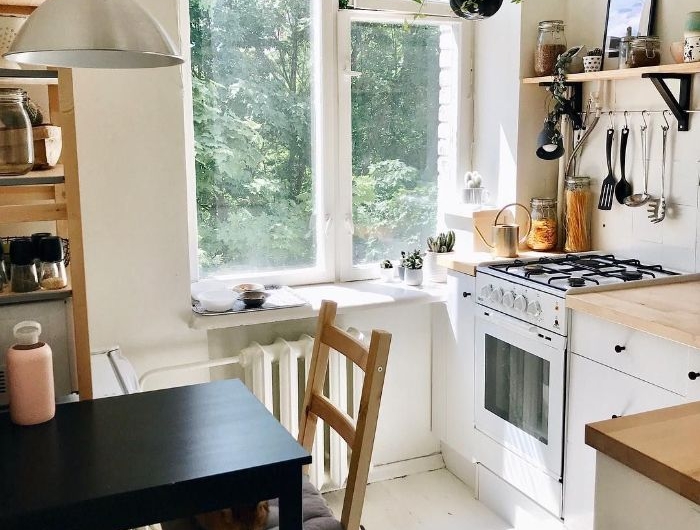 petite cuisine en l blanche avec des plans de travail noirs table salle à manger noire plantes suspendues