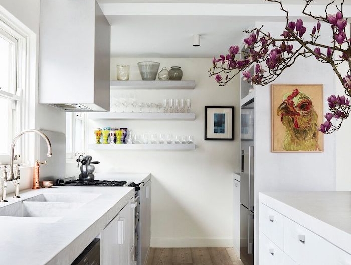 petite cuisine en longueur en blanche avec des etageres au mur et une branche aux fleurs violets