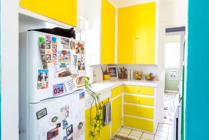 portes placards et tiroirs de cuisine repeintes de couleur jaune vitamintée plans de travail blancs frigo blanc cuisine petit espace design