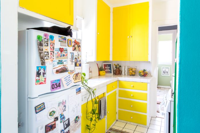 portes placards et tiroirs de cuisine repeintes de couleur jaune vitamintée plans de travail blancs frigo blanc cuisine petit espace design