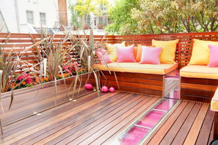 quel amenagement petites terrasse de bois avec assise bois coussins colorés rose et jaune bordure fleuri