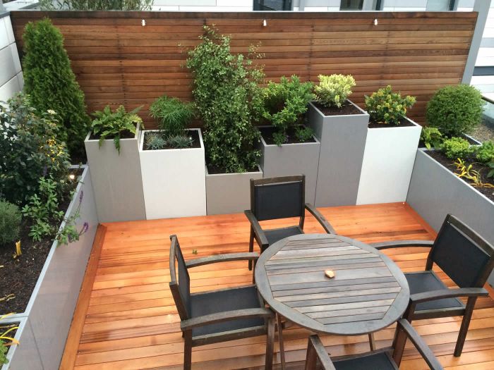 quel aménagement extérieur terrasse habillée de bois avec table ronde bois et chaises jardin brise vue bois et jardinièrs avec plantes vertes