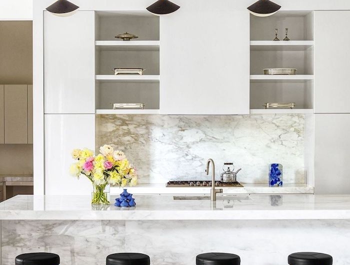 un aménagement moderne petite cuisine avecdes surfaces en marbre lapes pendantes et bar chaises