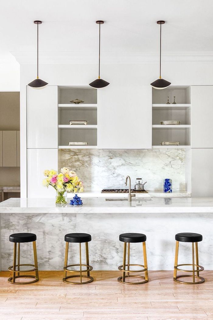 un aménagement moderne petite cuisine avecdes surfaces en marbre lapes pendantes et bar chaises