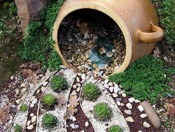 un grand pot de fleurs qui verse des pierres decoratifs autour des succulents jardin gravier decoratif