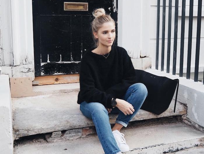 un look casual américain avec des jeans enroulé et un pull noir une fille assise devant une porte