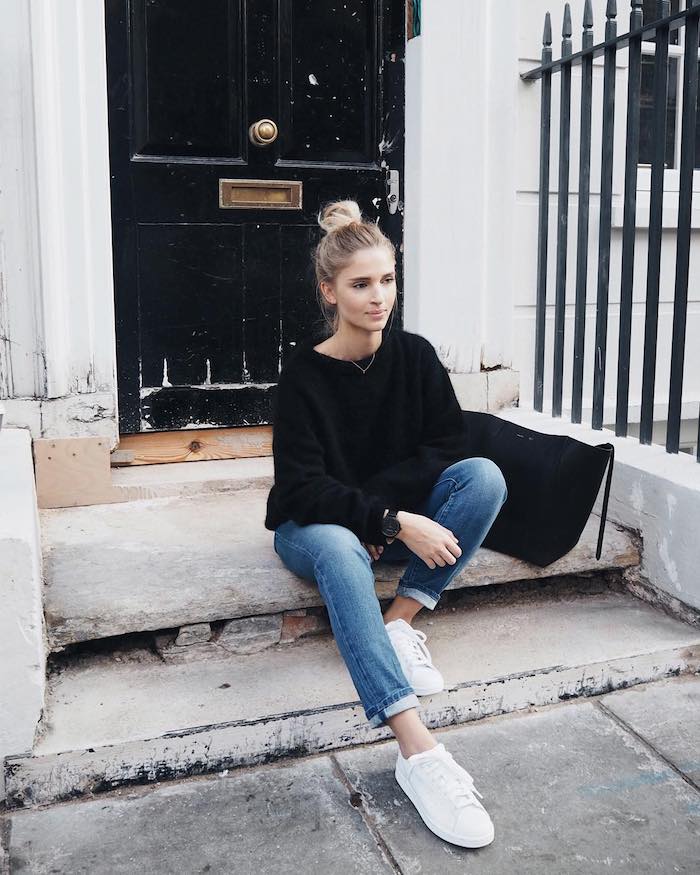 an American casual look with rolled up jeans and a black sweater a girl sitting in front of a door