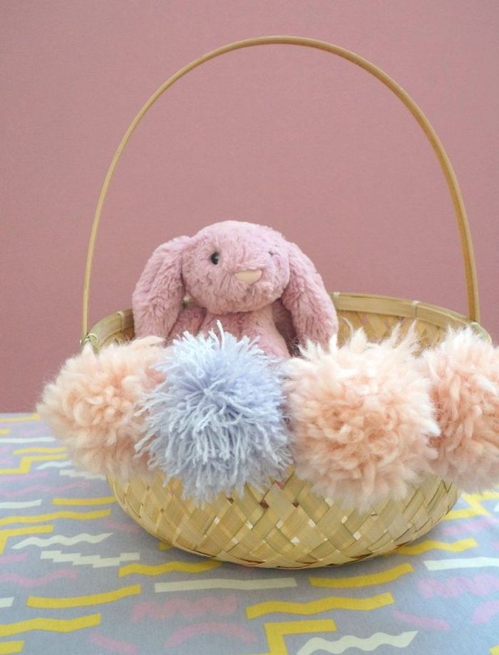 un panier en paille décoré avec des pompons et un lapin en pelouche mignon décoration de paques a fabriquer