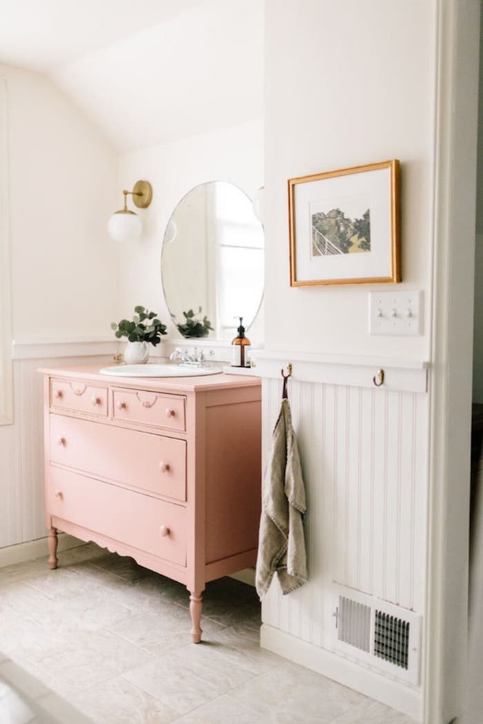 une chambre en blanc avec miroir rond suspendu au dessus d un commode vieux rose peinture