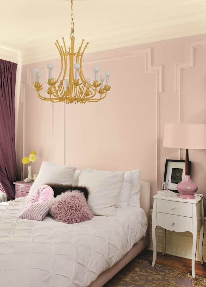 une chambre rose et blanc avec un abat jour dore suspendu au plafond et des rideaux couleur vieux rose