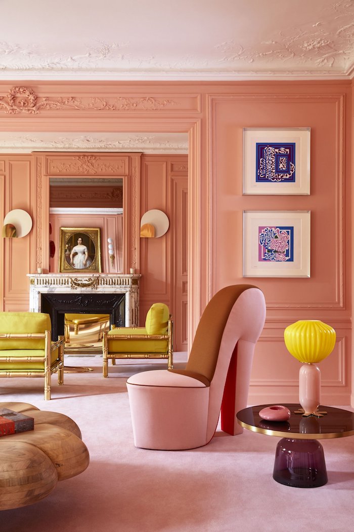 une chambre vieux rose en style haussmanien avec des meubles jaunes et un fauteil rose en forme d escarpin