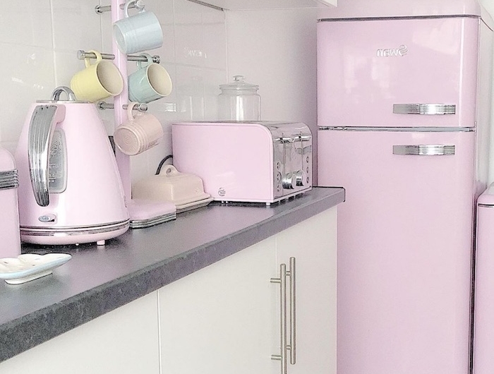 une cuisine avec des placards en blanc et des apareils et un frigo en couleur rose pastel