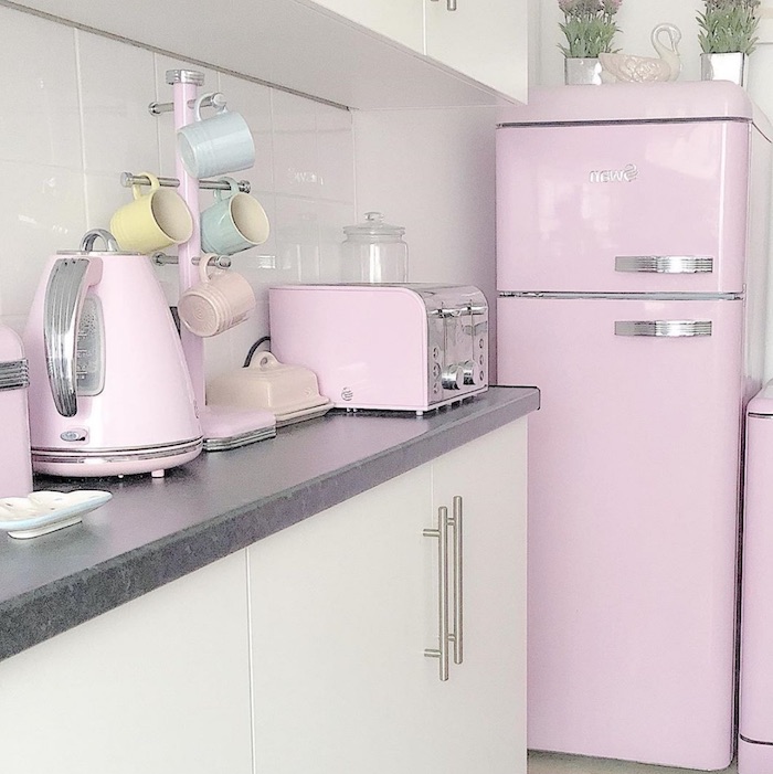une cuisine avec des placards en blanc et des apareils et un frigo en couleur rose pastel