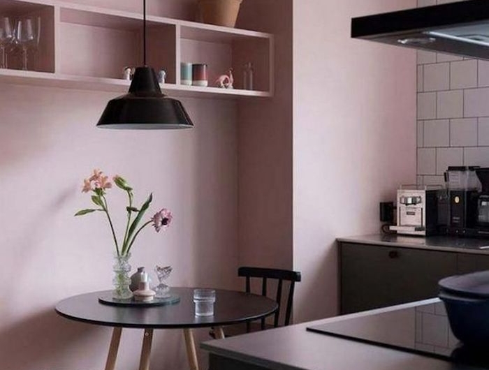 une cuisine en couleur rose pastel au murs et des meubles et appareils noirs