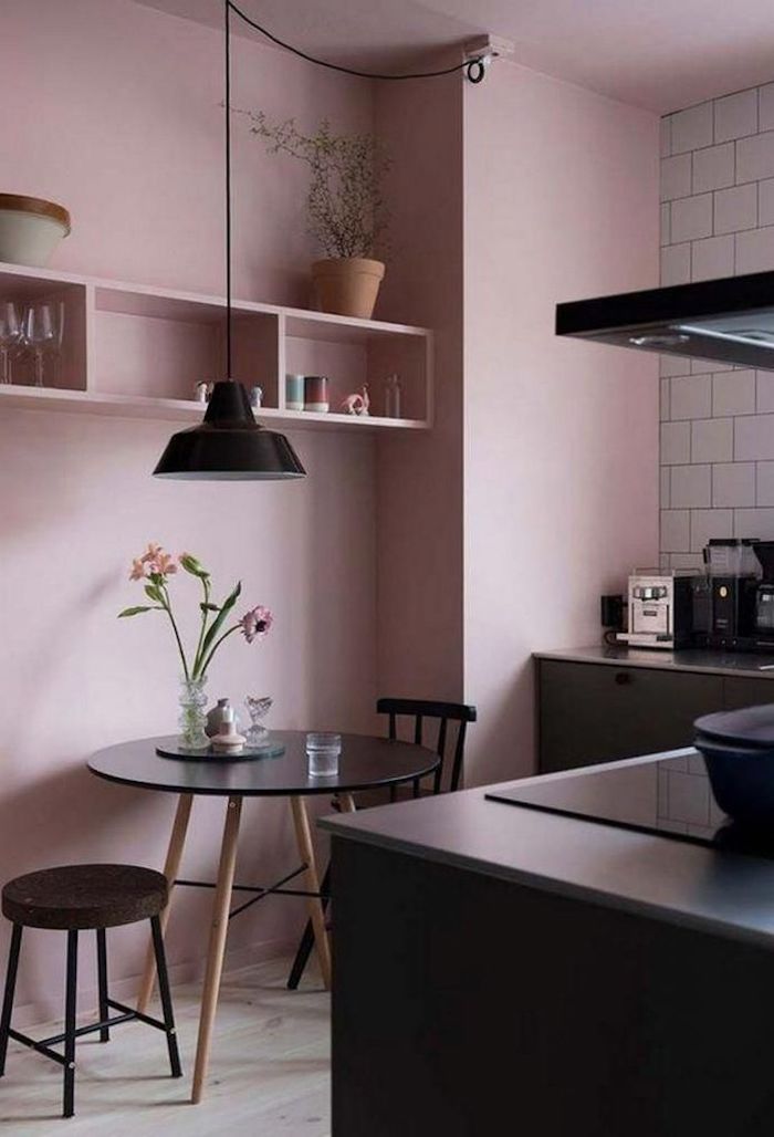une cuisine en couleur rose pastel au murs et des meubles et appareils noirs