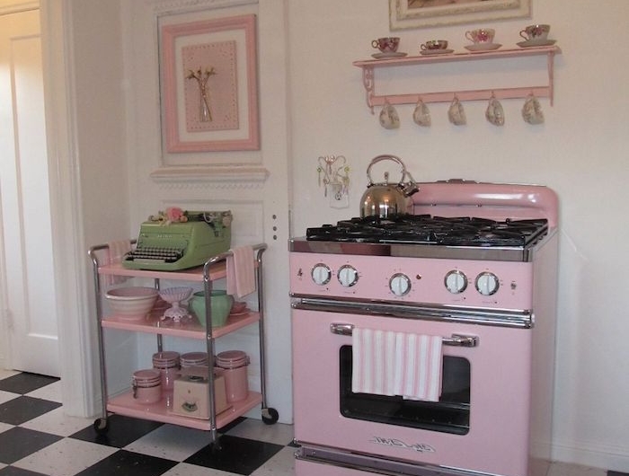 une cuisine vintage avec du carrelage noir et blanc au sol et un four en peinture rose pale