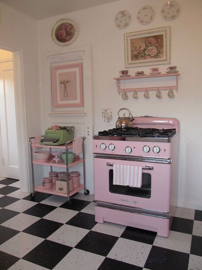 une cuisine vintage avec du carrelage noir et blanc au sol et un four en peinture rose pale