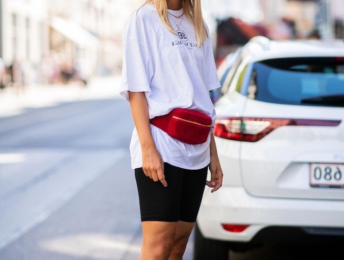 une femme blonde vetue en style casual chic avec des baskets tee shirt blan et sac rouge autour la taille