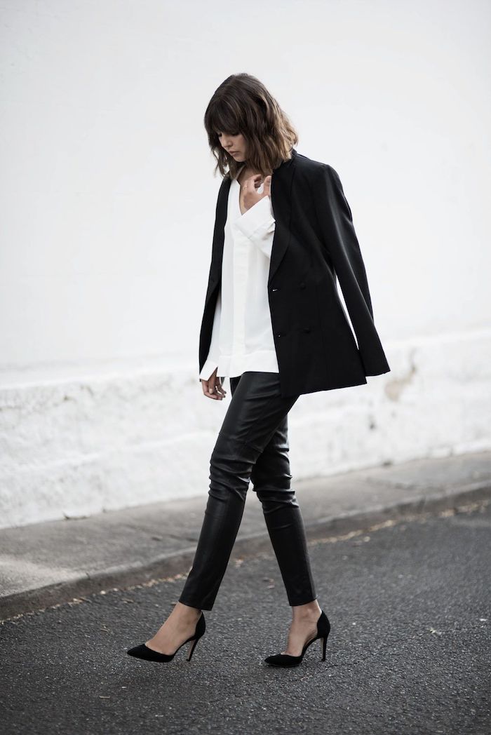 une femme en tenue style qui comporte pantalon en cuir chemisier blanc et une veste noir