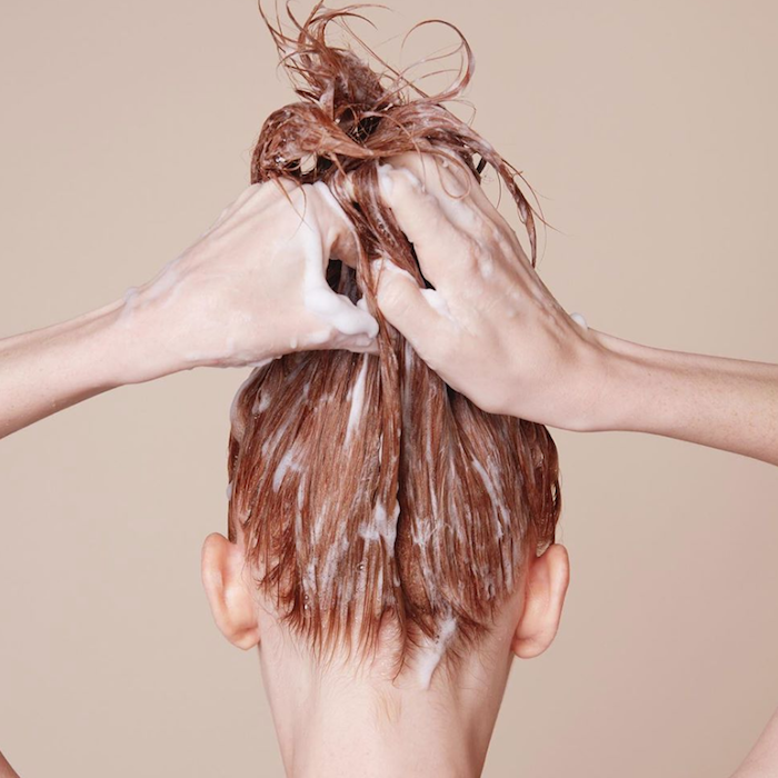 une femme qui tige ses cheveux onctués d un masque en haut avec des mains.jpg