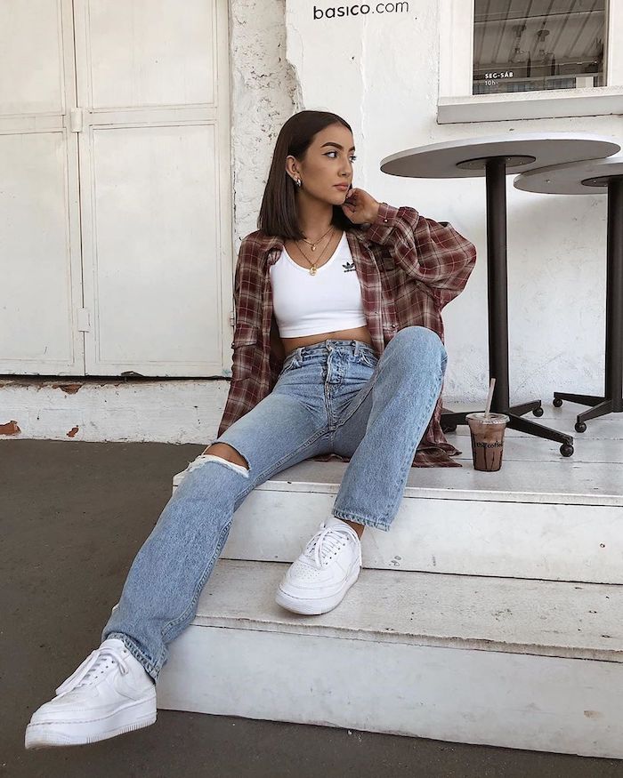 a girl at the escaleir wearing white sneakers, ripped jeans and a plaid shirt