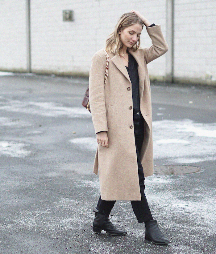 une idée tenue femme en style minimaliste avec un manteau longue beige et des bottes en cuir noires garde-robe minimaliste
