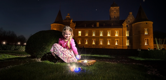 une petitte fille qui collecte des oeufs dans le jqrdn devant un chateau