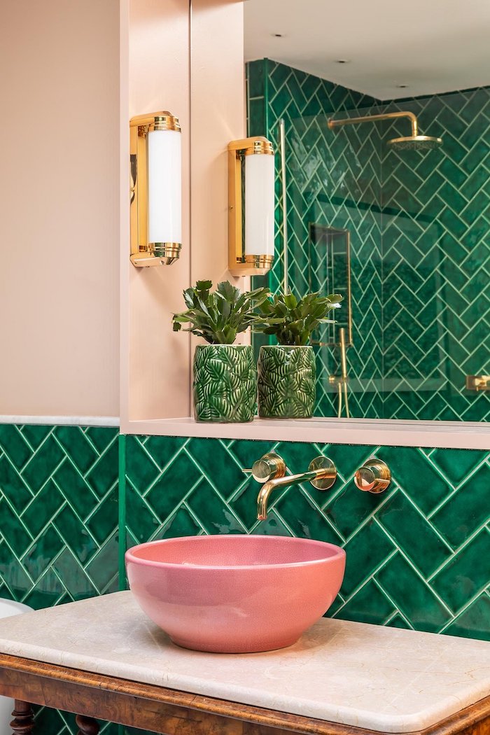 une salle de bain avec de carrelage vert des elements dores et un lavabo couleur complémentaire rose