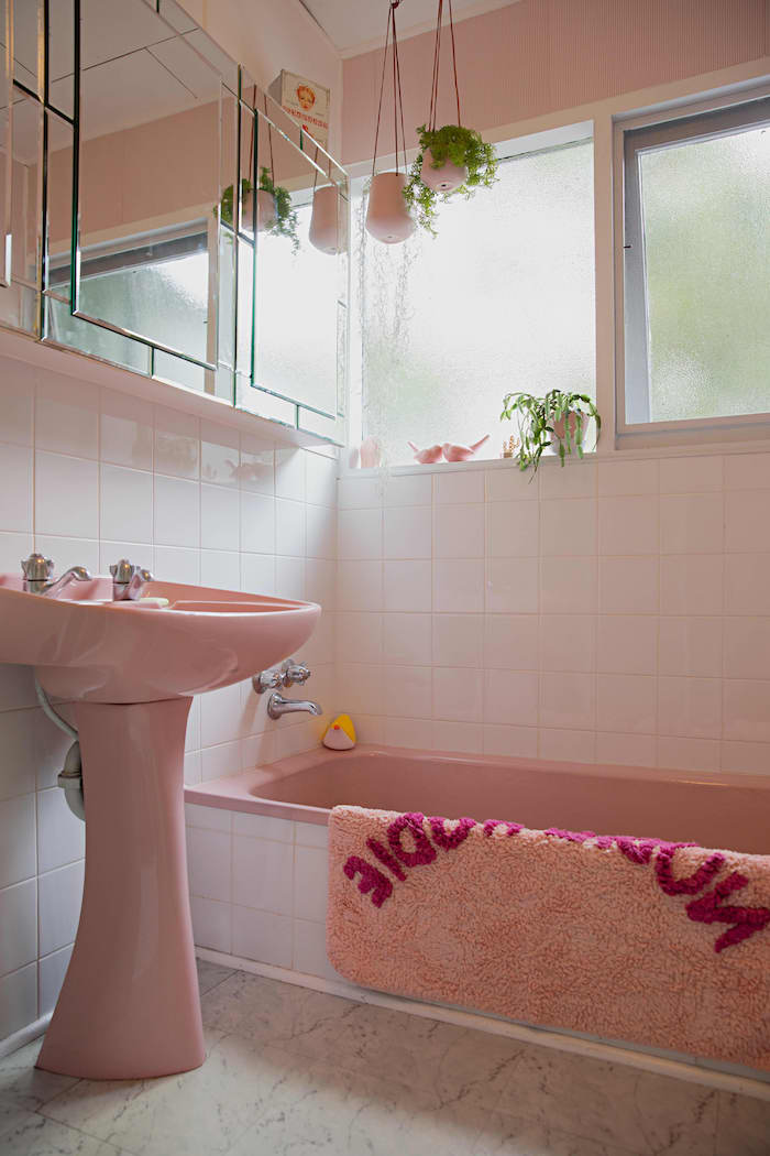 une salle de bain en style vintage avec un baignoir et lavabo en peinture vieux rose et des pots a fleurs suspendus