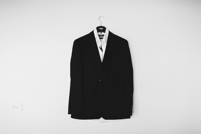 une veste noir style boyfriend accroché a un cintre avec un col blanc