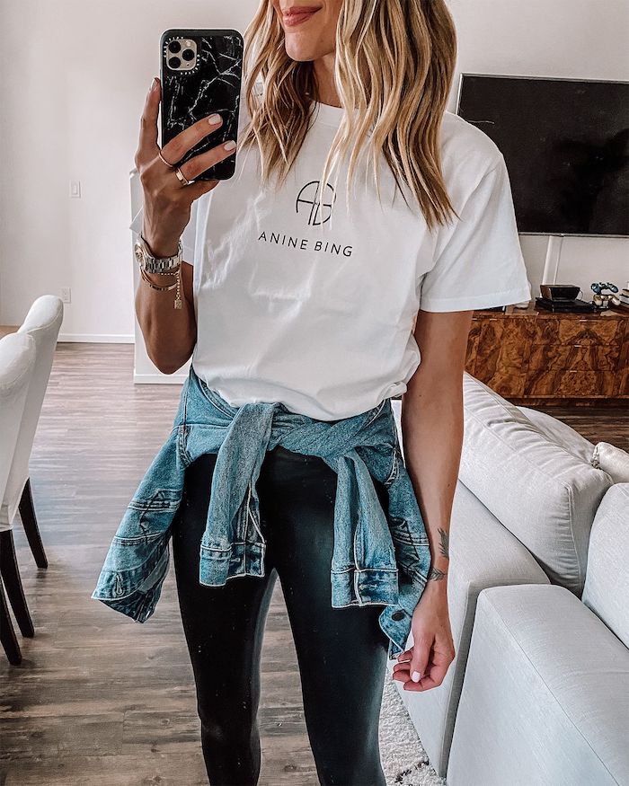 American denim jacket tied around the waist combined with a white t-shirt and black pants