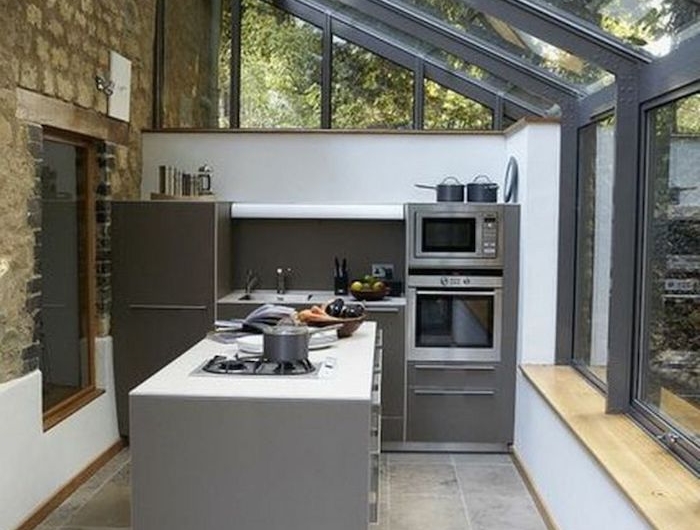 aménagement veranda 15m2 souus un toit en verre et des meubles et appareils a cuisson modernes