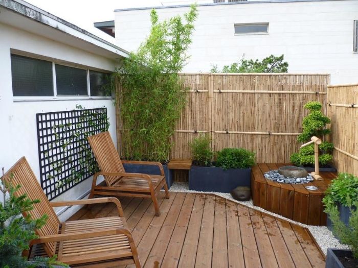 balcon terrasse de bois avec chaises boisés petit bassin de jardin arbustes verts et palissade bambou