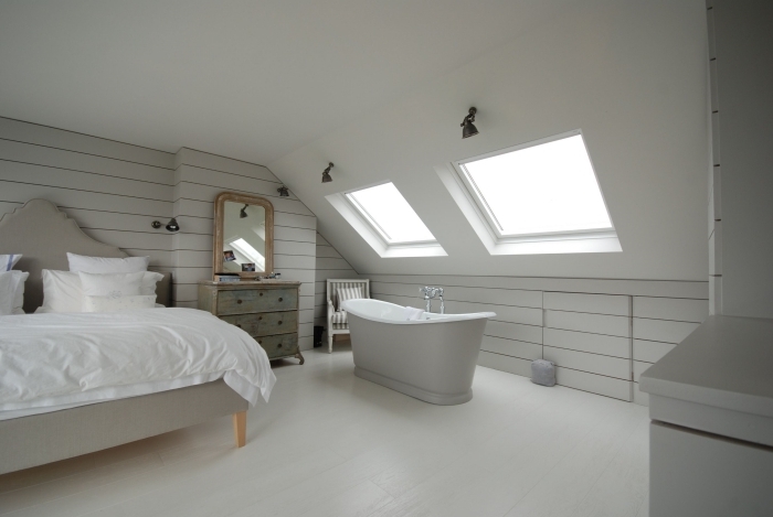 chambre sous pente avec baignoire autoportante éclairage moderne fenetre de toit lit miroir vintage