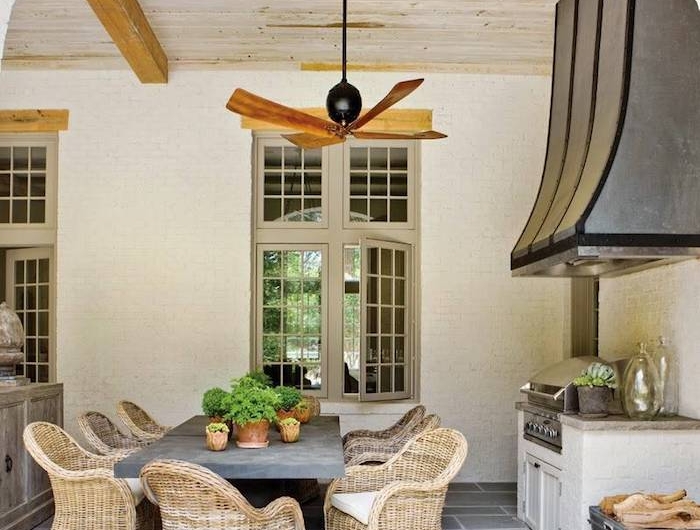 comment aménager une veranda pour salle a manger avec des meubles en rtoin ert un ventialteur au plafond
