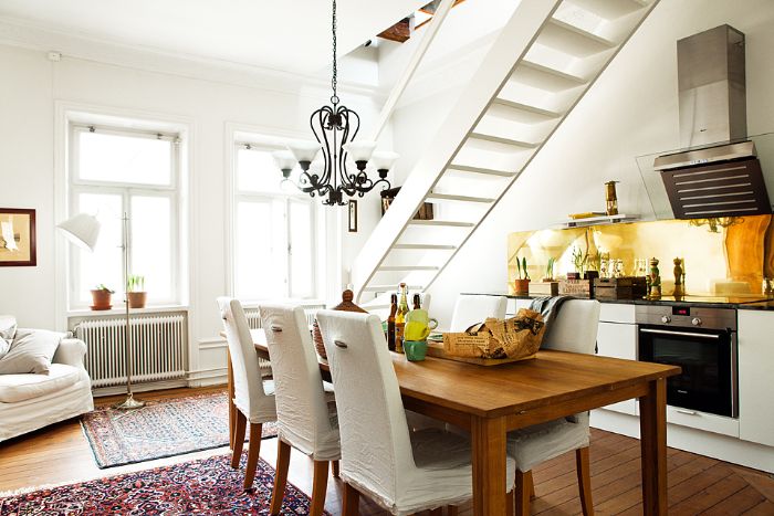 credence effet laiton doré meuble bas blanc table bois chaises habillées de tissu parquet bois clair tapis orientaux aménagement sous escalier ouvert