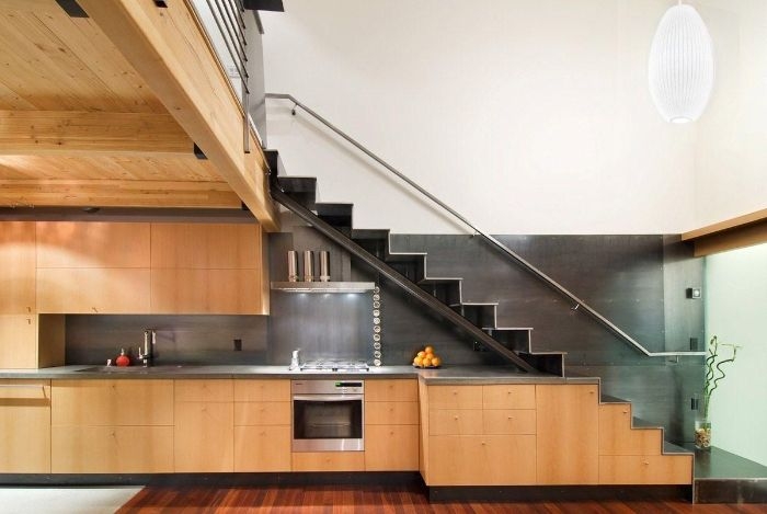 cuisine bois avec plan de travail inox sous escalier avec rambarde de verre parquet bois clair suspension blanche originale