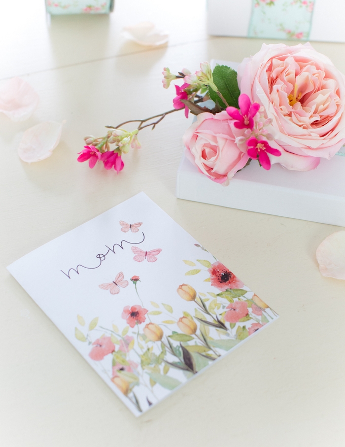 des fleurs artificiels sur un table a coté d d un carte fête des mères