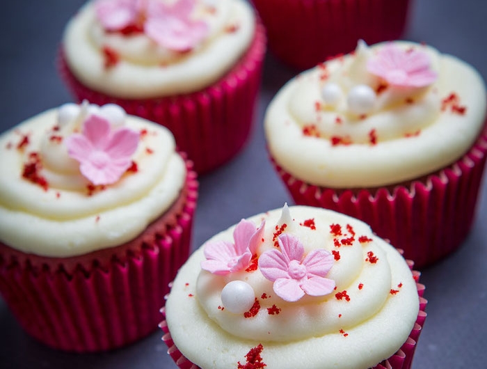 des jolis muffins en papier rose avec des petites fleurs au dessus de glacage