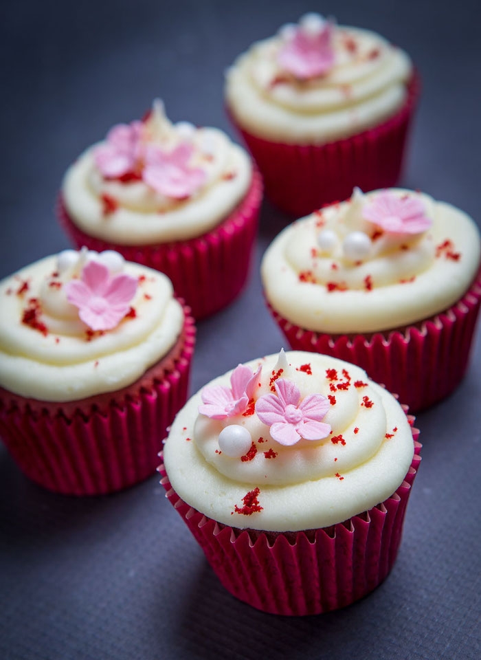 des jolis muffins en papier rose avec des petites fleurs au dessus de glacage