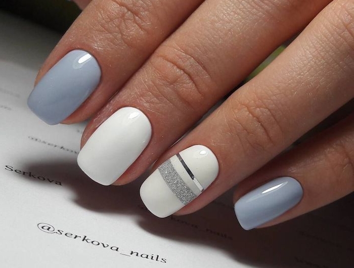 des ongles teint en vernis pastel blanc et bleu avec des lignes en paillettes