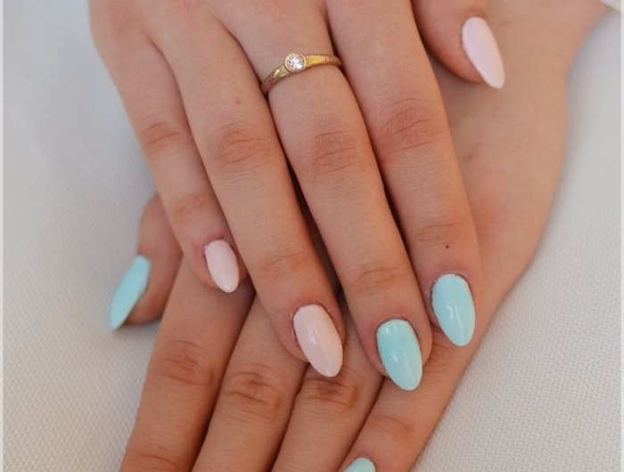 deux mains avec un anneau et manucure en deux couleurs bleu et rose pastel