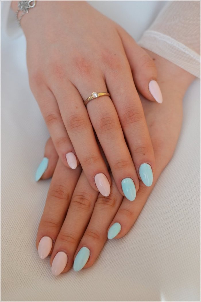 deux mains avec un anneau et manucure en deux couleurs bleu et rose pastel