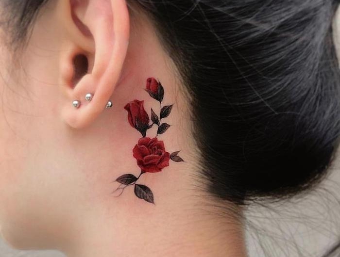 femme cehveux noirs avec tatouage fleur minimaliste derrièer l oreille